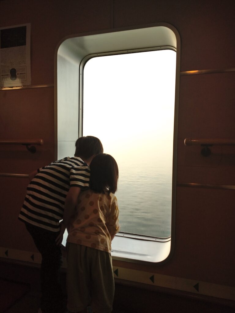 フェリーさんふらわあ船内の窓から海原を眺める子ども達