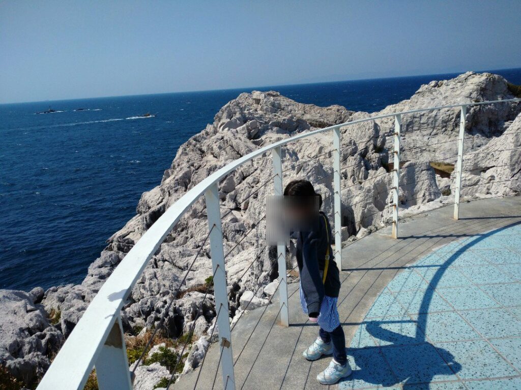 日本(和歌山)のエーゲ海、白崎海洋公園にて。青い海と石灰岩を眺める子。